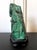A malachite rock specimen with intense green and black colors fitted on a wood stand and displayed as a <a...