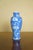 A decorative Chinese blue-and-white porcelain vase featuring white prunus blossoms against a soft blue cracked-ice ground....