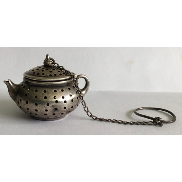Adorable little sterling silver loose tea strainer in the shape of a tiny tea pot with hinged lid . Marked on bottom .