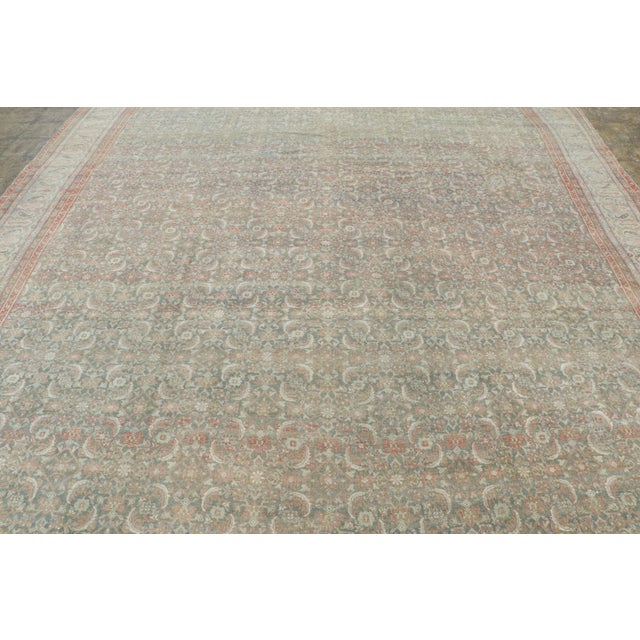 This antique 11x15 Persian Mashad rug is a graceful early 20th-century carpet distinguished by its densely ornamented...