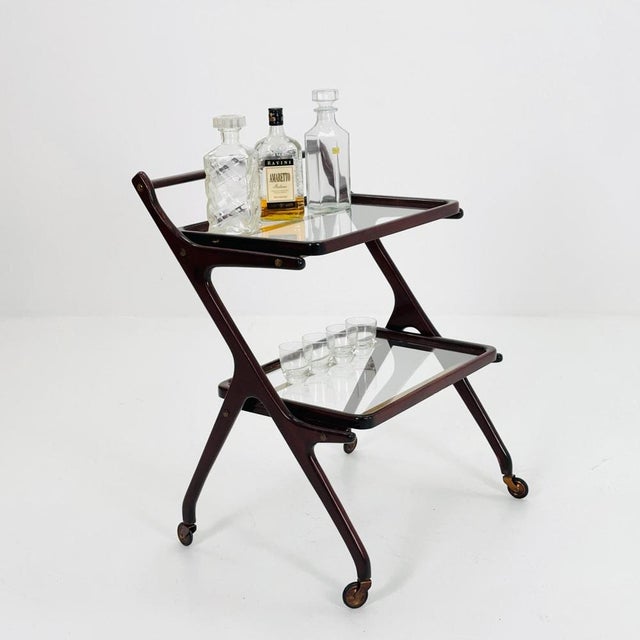 Vintage 1950s Italian Bar Cart designed by Cesare Lacca. Crafted in stained walnut with brass accents, it features two...