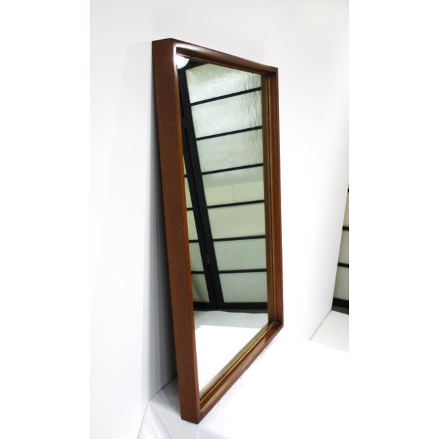 A dark maple wood wall mirror designed by Paul McCobb and manufactured by the Winchendon Furniture company from their...