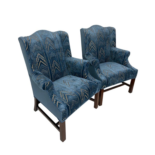This elegant pair of wingback armchairs has been newly upholstered. The patterned cut velvet on the seat, arms, and...