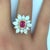 A fine and elegant ruby is set in the middle of this diamond sunburst designed ring! The ruby has a rich pure red color...