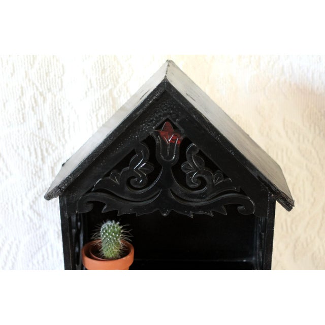 A wall shelf with 2 shelves shaped like a house with cutouts and black and red painting. Folk or rustic style with tulips....