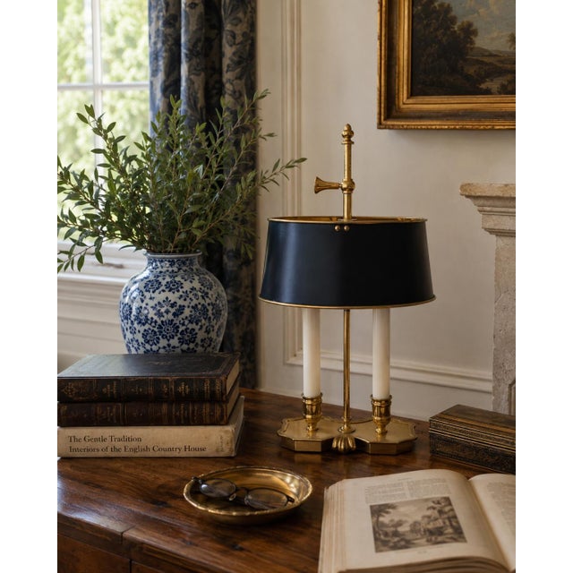 A handsome mid-20th-century brass bouillotte lamp with a tailored black tole shade and classic two-light configuration....
