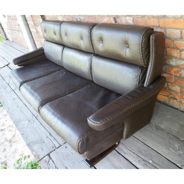 A three-seat sofa designed by Arne Norell, Sweden, around 1970, natural leather with a distinctive thong hem in the color...