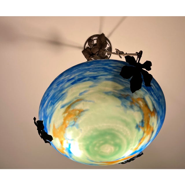 1920s Muller Frères chandelier with a wrought iron frame with a leaf and vine motif supporting a frosted art glass shade....
