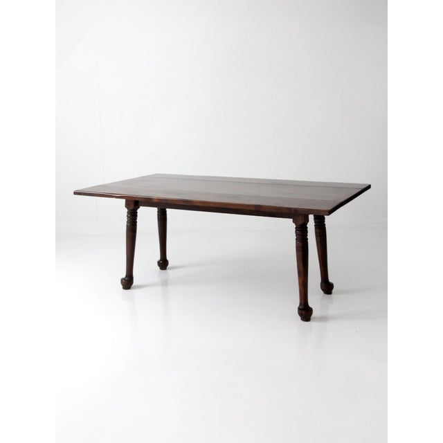 An Early American drop-leaf table with a long, narrow profile that gives it a distinct presence when closed, offering the...