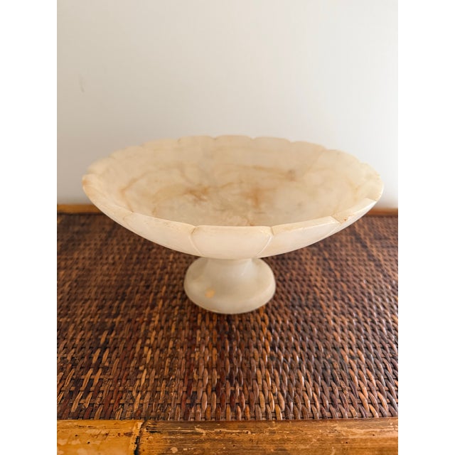 A beautifully carved vintage marble compote bowl featuring a delicate scalloped rim and classic pedestal base. The stone...