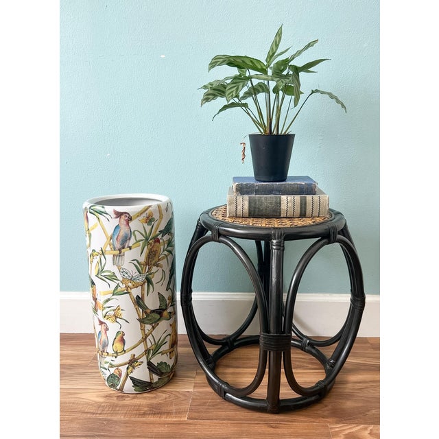 Handsome, vintage low rattan stool featuring a black finish, sculptural bent-rattan frame, and natural woven cane top. The...