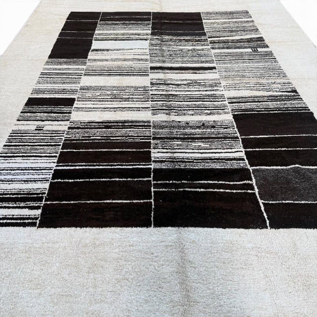 A striking contemporary rug crafted from reclaimed hemp and goat wool, featuring a bold abstract design of black linear...