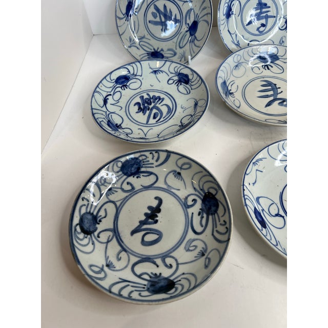 A charming collection of nine vintage Chinese blue-and-white porcelain small plates featuring hand-painted calligraphic...