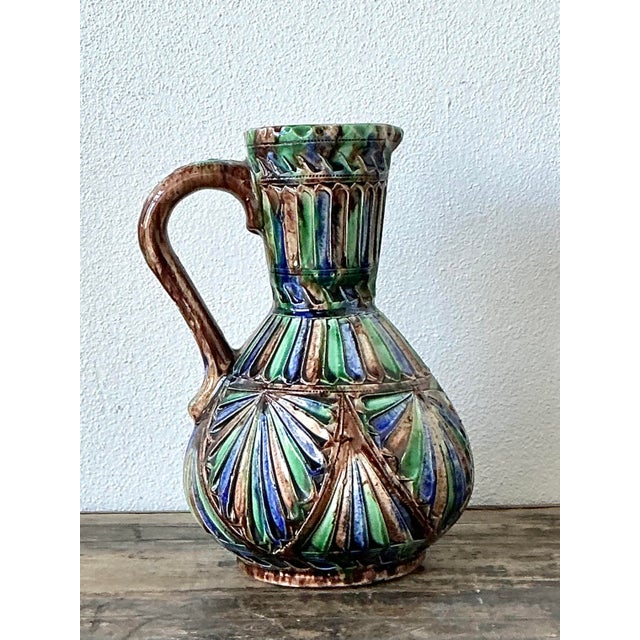 This vibrant vintage pitcher is a wonderful example of mid-century artisanal pottery, likely originating from Italy or...