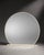 A large round mirror with a soft cream-colored frame and a clean sculptural base. The rounded silhouette and neutral...