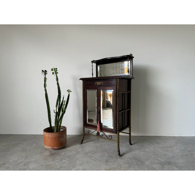 A magnificent 1900's Antique English mahogany and brass framed music cabinet. The cabinet design harmoniously blends...