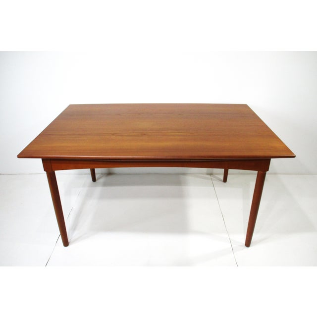 A large sized stunning expandable teak wood dining table with pull out leaves to each end having exceptional graining to...