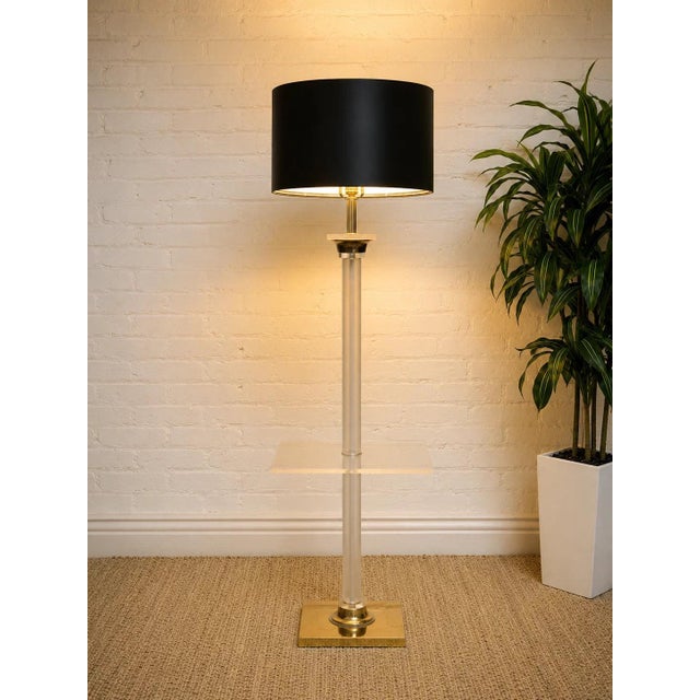 A striking vintage floor lamp combining clear Lucite, warm brass-tone accents, and a built-in square side table for a...