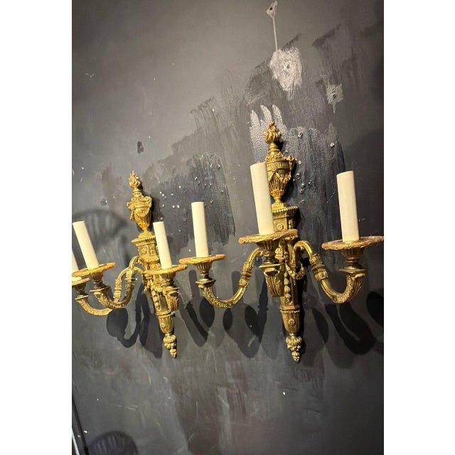 Circa 1900 pair of gilt bronze sconces by Caldwell with ram’s heads atop and flowers on the body. 3 lights sconces, newly...
