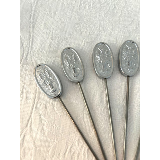 Vintage set of eight Towle silver shaded stainless steel skewers featuring a raised lobster motif at top. In original boxes.