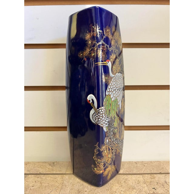 This square vase features detailed flowers and pheasants with gold accents, set against a cobalt blue background. It’s in...