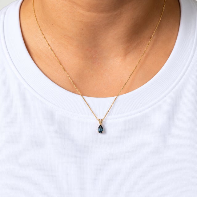 A 0.48ct london blue topaz pear pendant set in solid 14K yellow gold. London blue topaz is prized for its deep, inky blue....