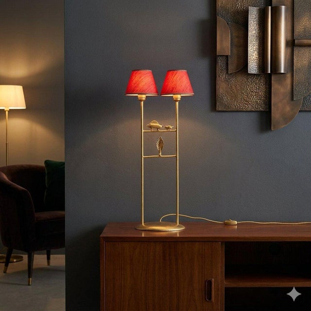 Gilded bronze sculpture lamp with two lights and a red fabric lampshade. This piece is attributed to the mentioned...
