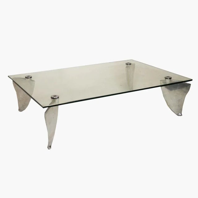 A vintage rectangular coffee table in glass and aluminium. This piece is attributed to the mentioned designer/maker. It...