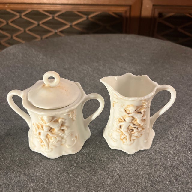 Miniature lidded creamer & sugar set with raised cherubs. Marked 215 on bottom.