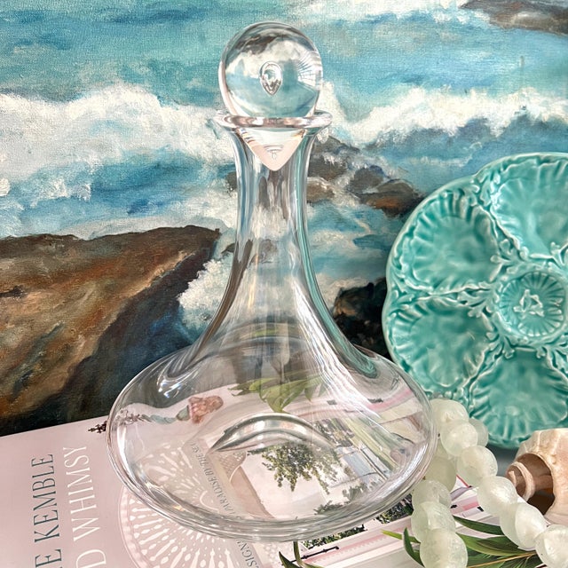 Steuben Glass decanter featuring a signature teardrop stopper. The hand-blown crystal piece has a heavy, wide base and...