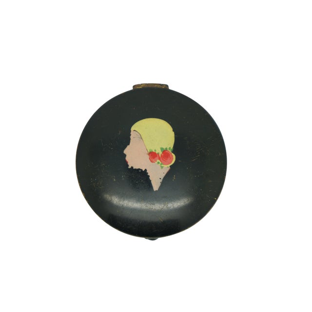 Two antique Art Deco Celma Co powder compact featuring enameled profiles of a flappers wearing hats against a black...