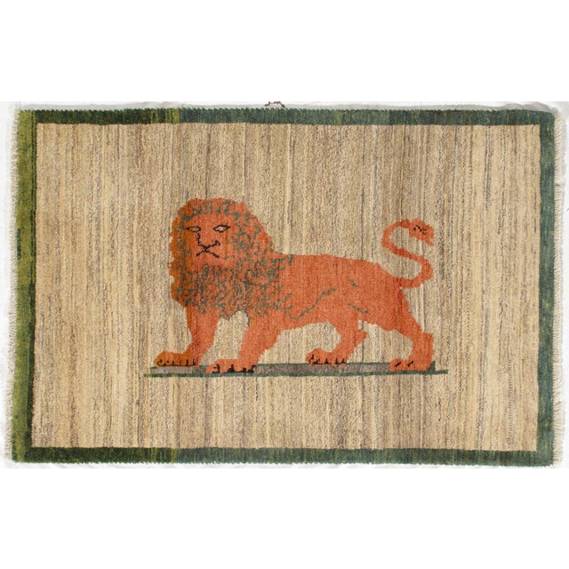 Vintage Persian hand-knotted Lori Gabbeh wool rug featuring a stylized lion motif set against a softly striated beige...