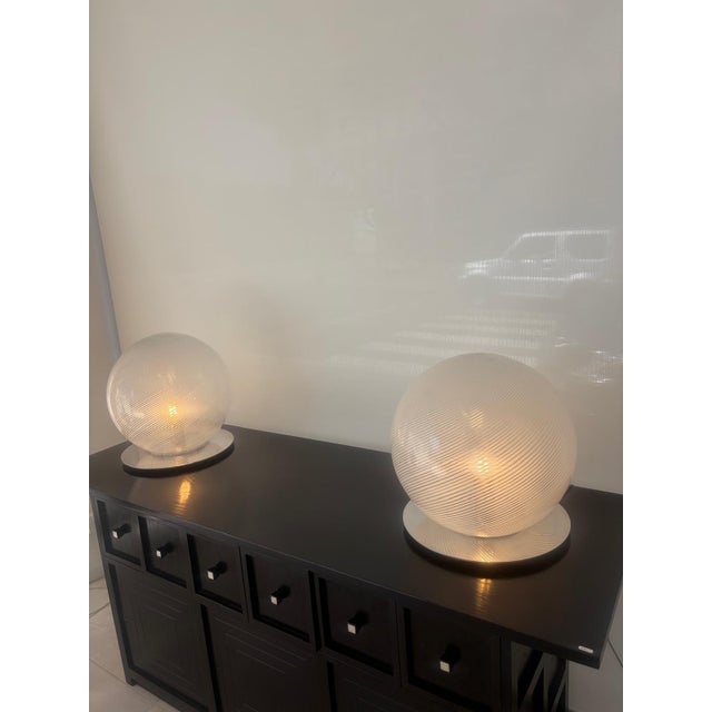 Pair of table lamps produced by Venini, 1970s, in Murano glass with spiral fabric and chrome base. This piece is...