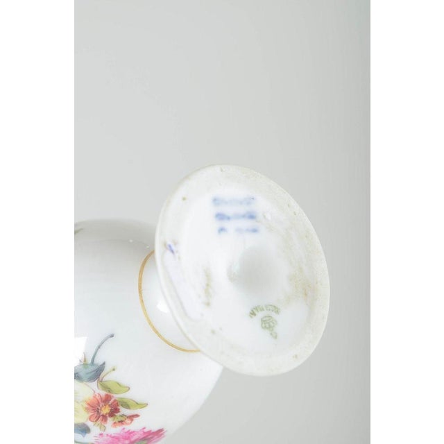 Royal copenhagen saxon flower egg cups, c. 1900. Three porcelain egg cups, two with fixed saucers, decorated with hand-...