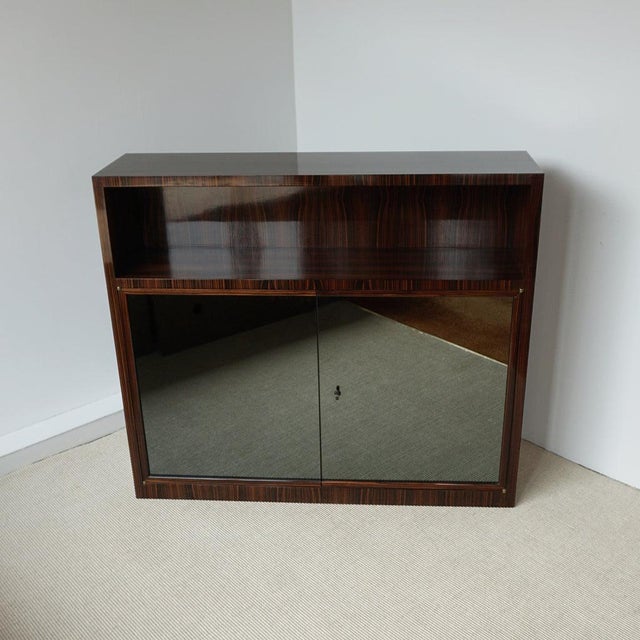 An Art Deco frosted mirror fronted bookcase cabinet. Macassar ebony veneered with an open upper shelf and single interior...