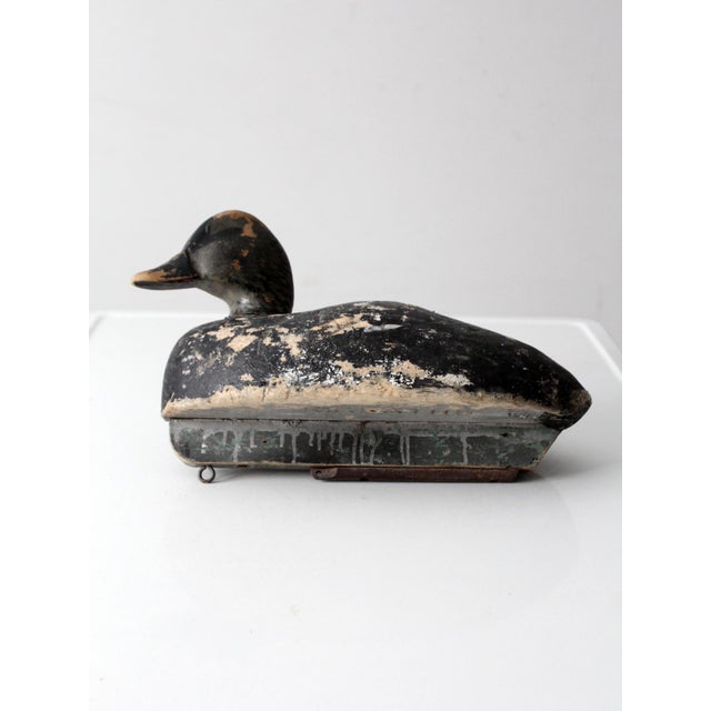 A striking antique hand-carved duck decoy with a sculptural silhouette and beautifully timeworn painted surface. Signed by...