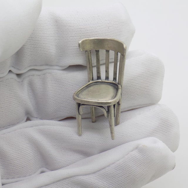 This vintage silver decorative object depicts a kitchen chair dollhouse miniature, crafted as a vitrine centerpiece,...