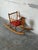 This charming children's rocking horse features a vibrant red seat and a classic spindle backrest. Built with smooth...