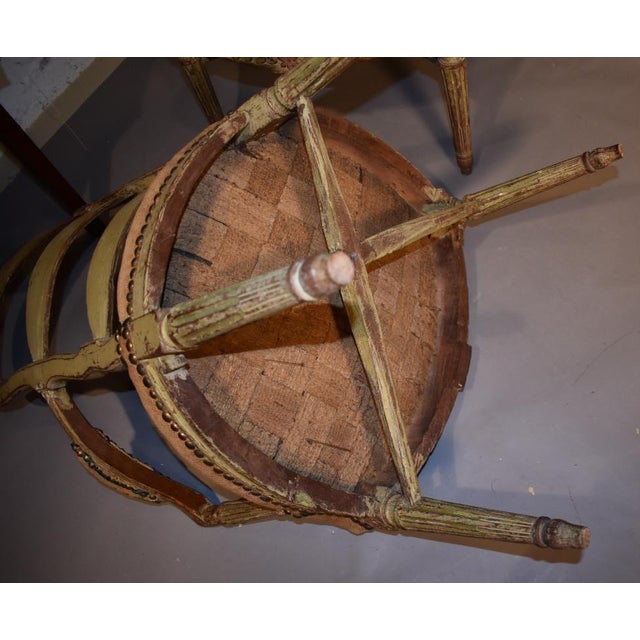 A true pair of Louis XVI country armchairs. of the late 1700s. Ladder backs and cushioned arms are above a shield-form...