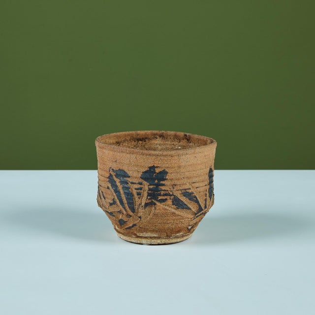 Hand thrown stoneware table planter. The planter features a ribbed exterior with incised detail and a painted black glaze...