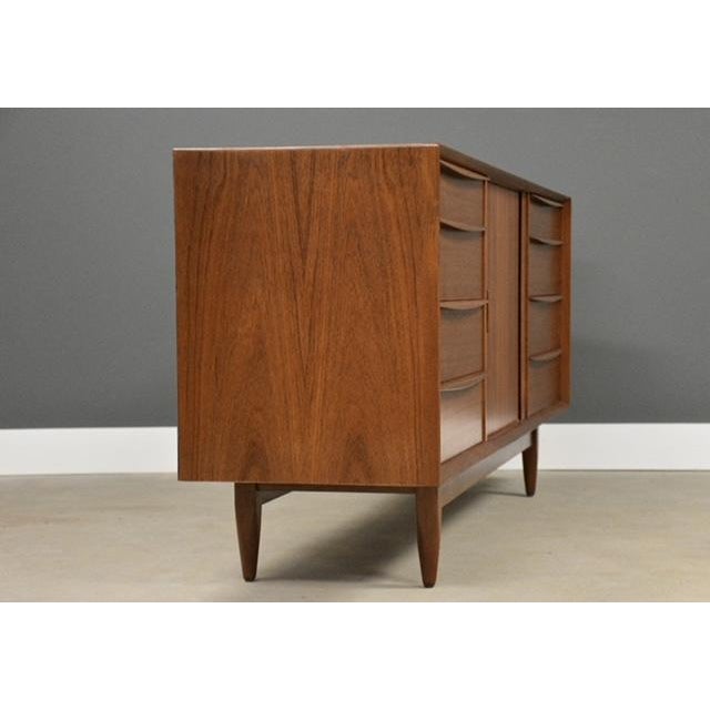 A mid century modern teak sideboard credenza with twelve dovetail dresser drawers by Falster. Sliding tambour door that...