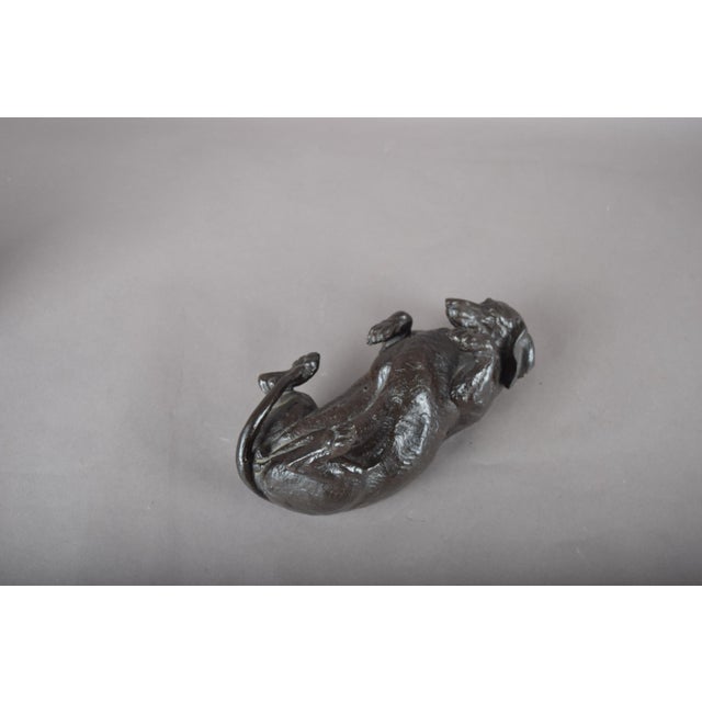 Rolling Dachshund sculpture by Doris Lindner, depicting a dog lying on its back with paws raised. Cast resin with a...