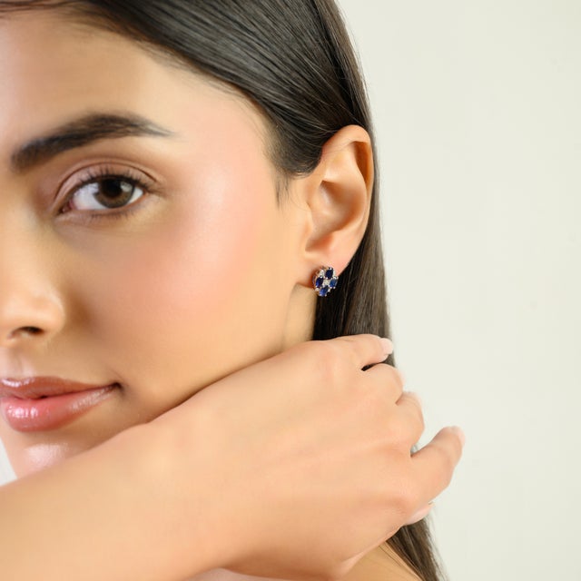 Beautifully crafted silver stud earrings featuring a striking cluster design of deep blue sapphires accented with...