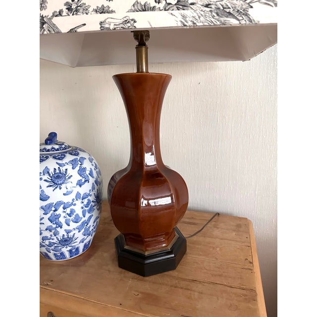 Tall faceted vintage ceramic lamp Rich rust color glaze Tall shaft with bulbous bottom Sits on dark wooden base with gold...