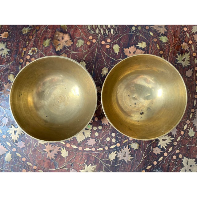 A pair of small bronzed Tibetan singing bowls with lovely engravings on the side. Each has a distinct pitch, with a warm...