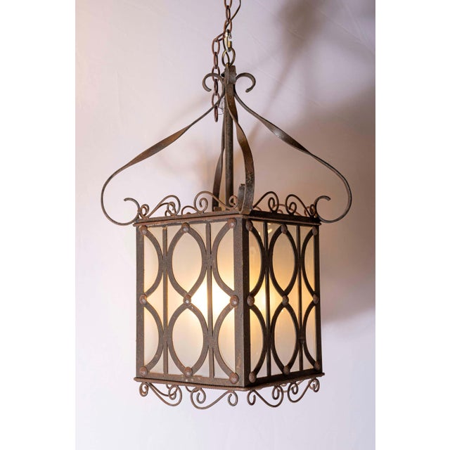 This is a stunning pair of early 20th-century French iron hanging lanterns, showcasing exquisite craftsmanship and design....
