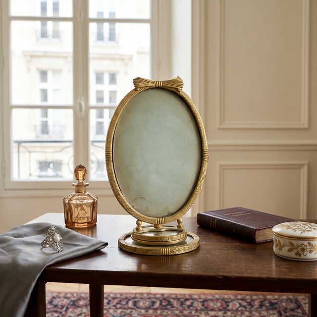 Antique French tabletop vanity frame in a Neoclassical style, constructed in gilt brass or bronze with an oval cross-...