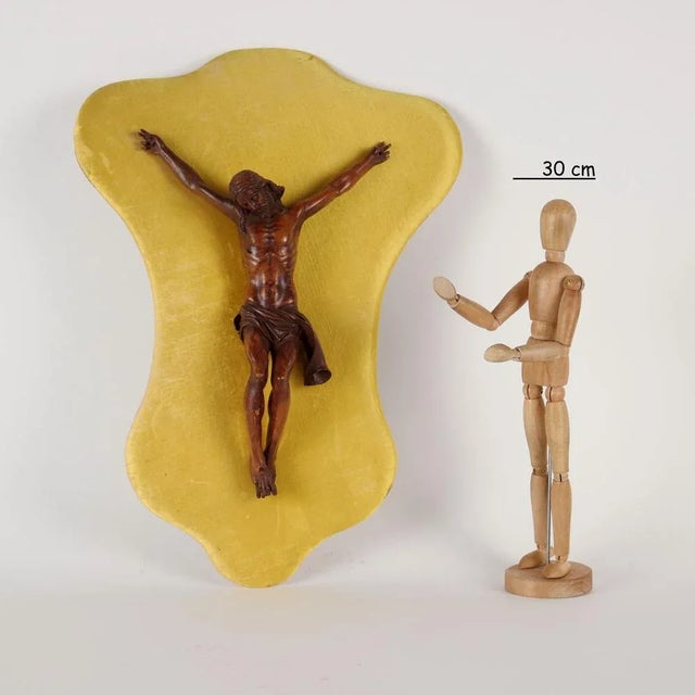 Crucified Christ in finely carved boxwood mounted on a panel covered in yellow fabric. This piece is attributed to the...
