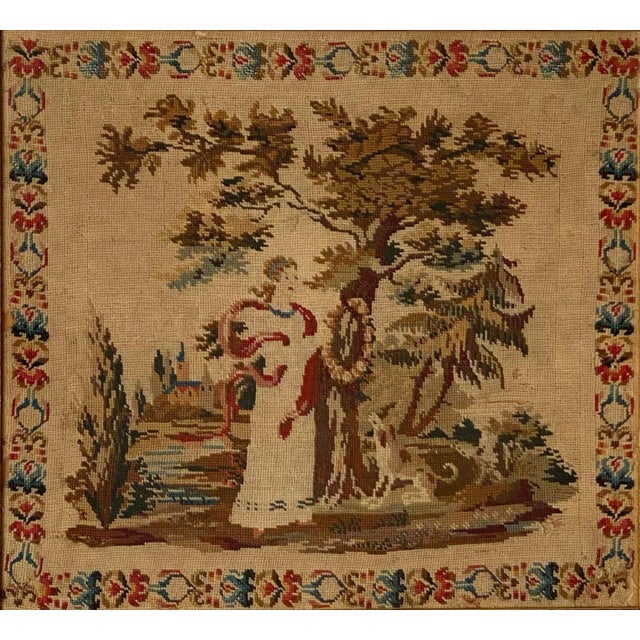 An early 19th Century English framed needlepoint of a woman and her dog standing in a garden.