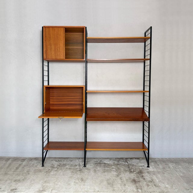 A two-bay ladderax shelving system by staples: three black metal ladders, two cabinets and six shelves. Everything hangs...